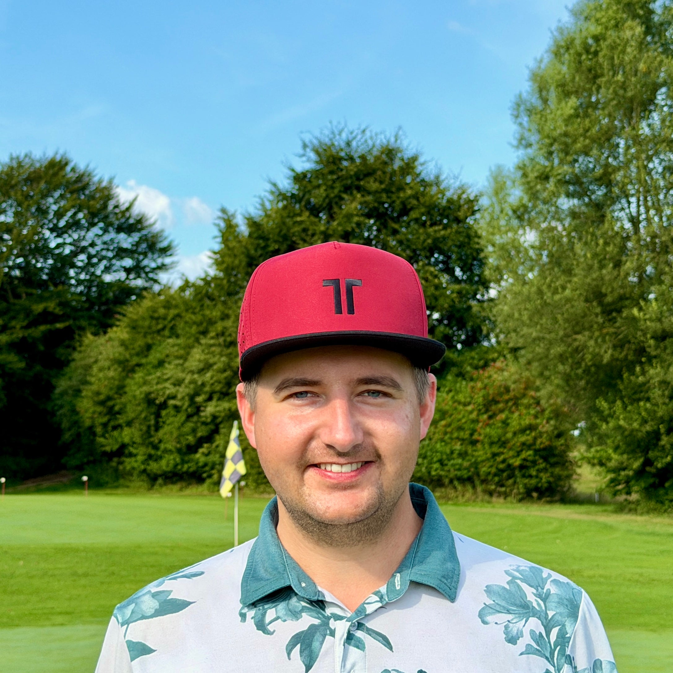 Person trägt THE CUTLINE Elite Cap in Burgunde auf dem Golfplatz