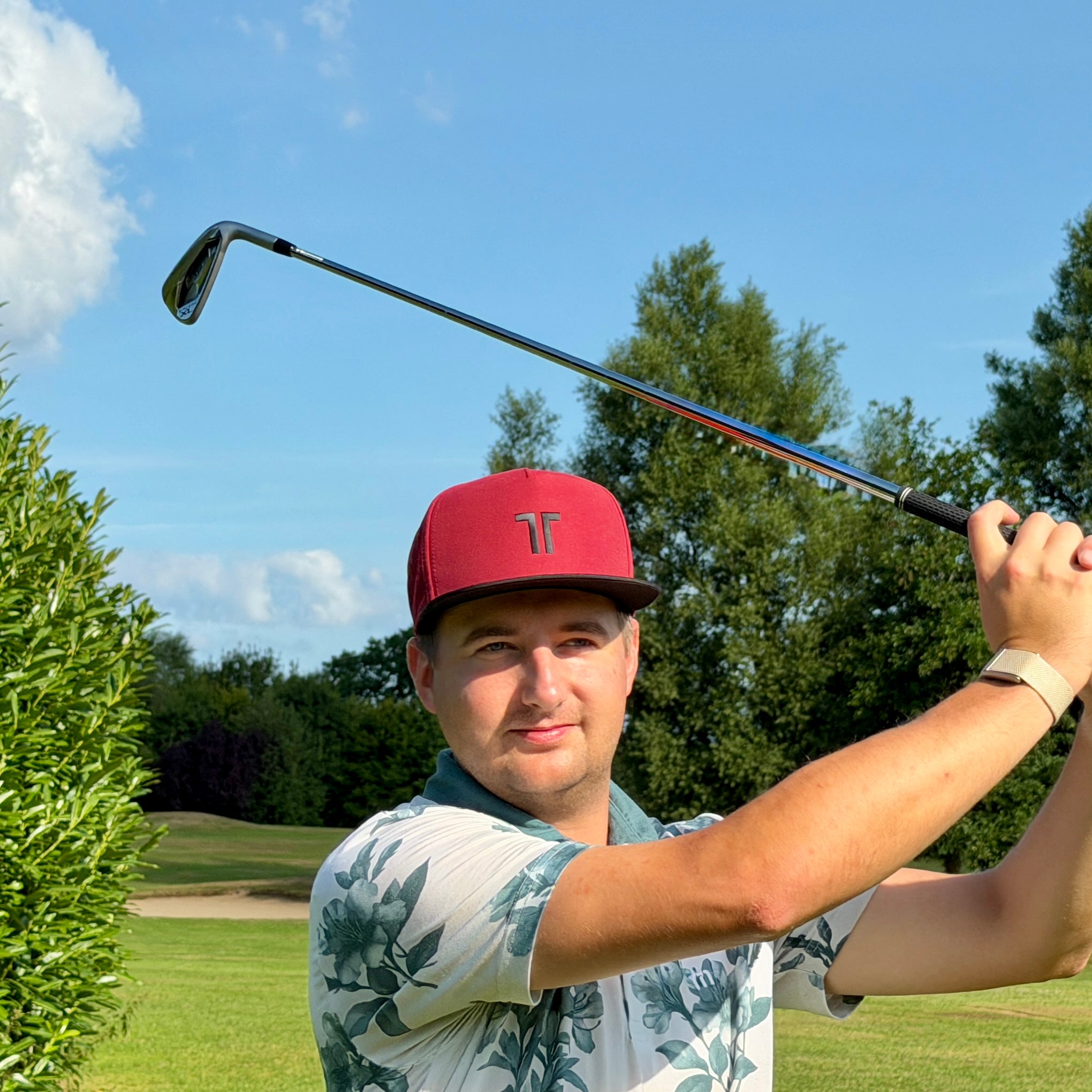 Person trägt THE CUTLINE Elite Cap in Burgunder beim Golfschwung