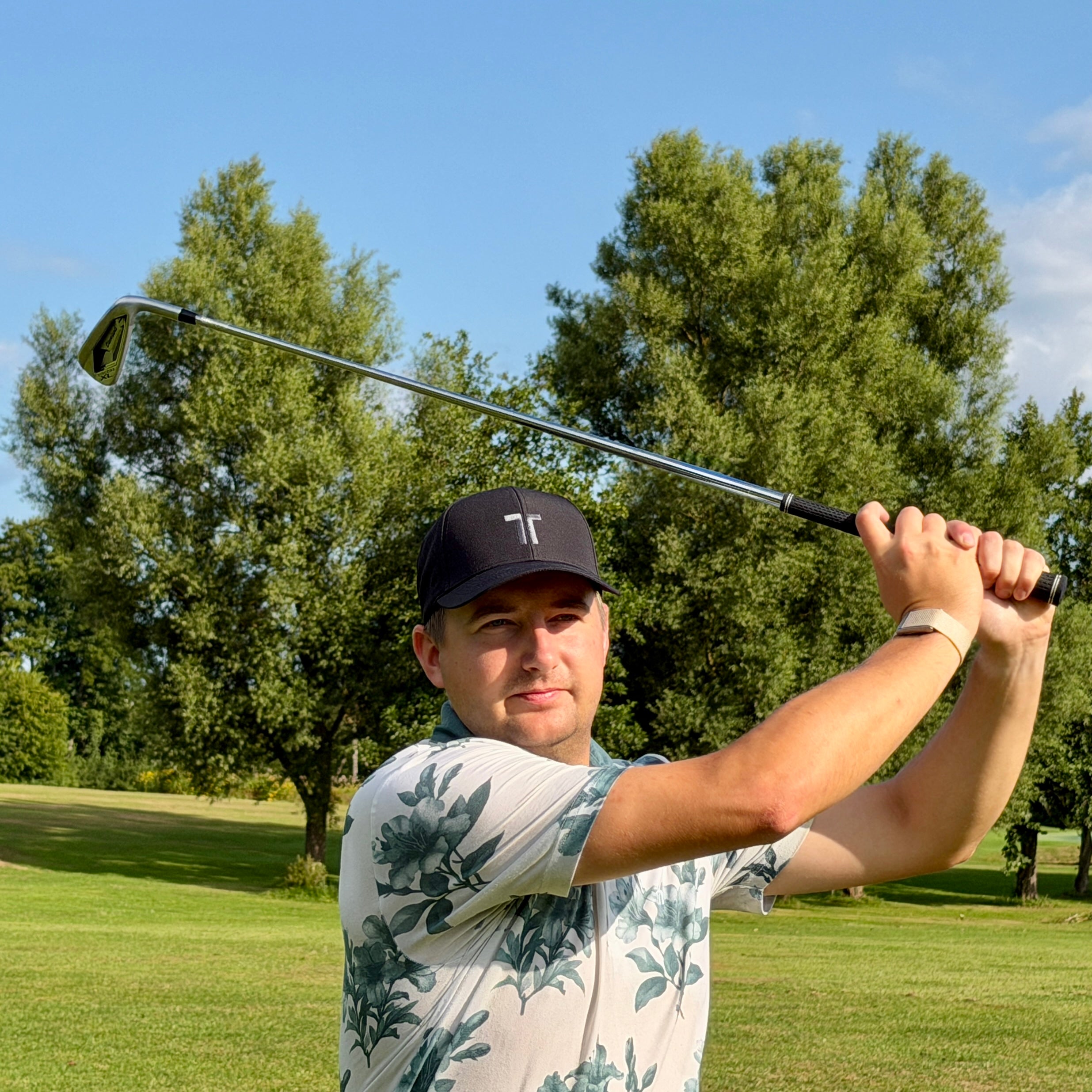 Person trägt THE CUTLINE Focus Cap in Schwarz beim Golfschwung