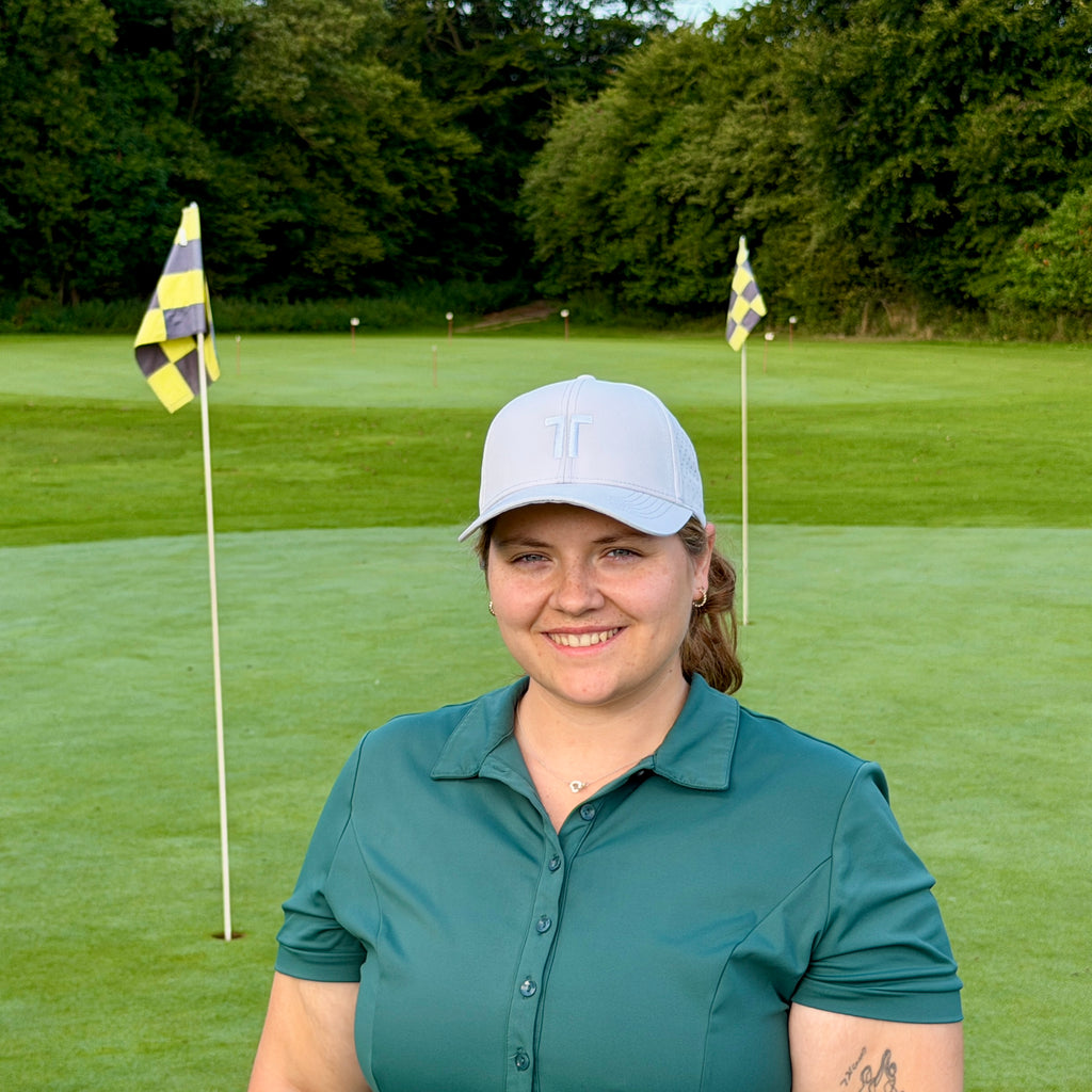 Person trägt THE CUTLINE Focus Cap in Weiß auf dem Golfplatz