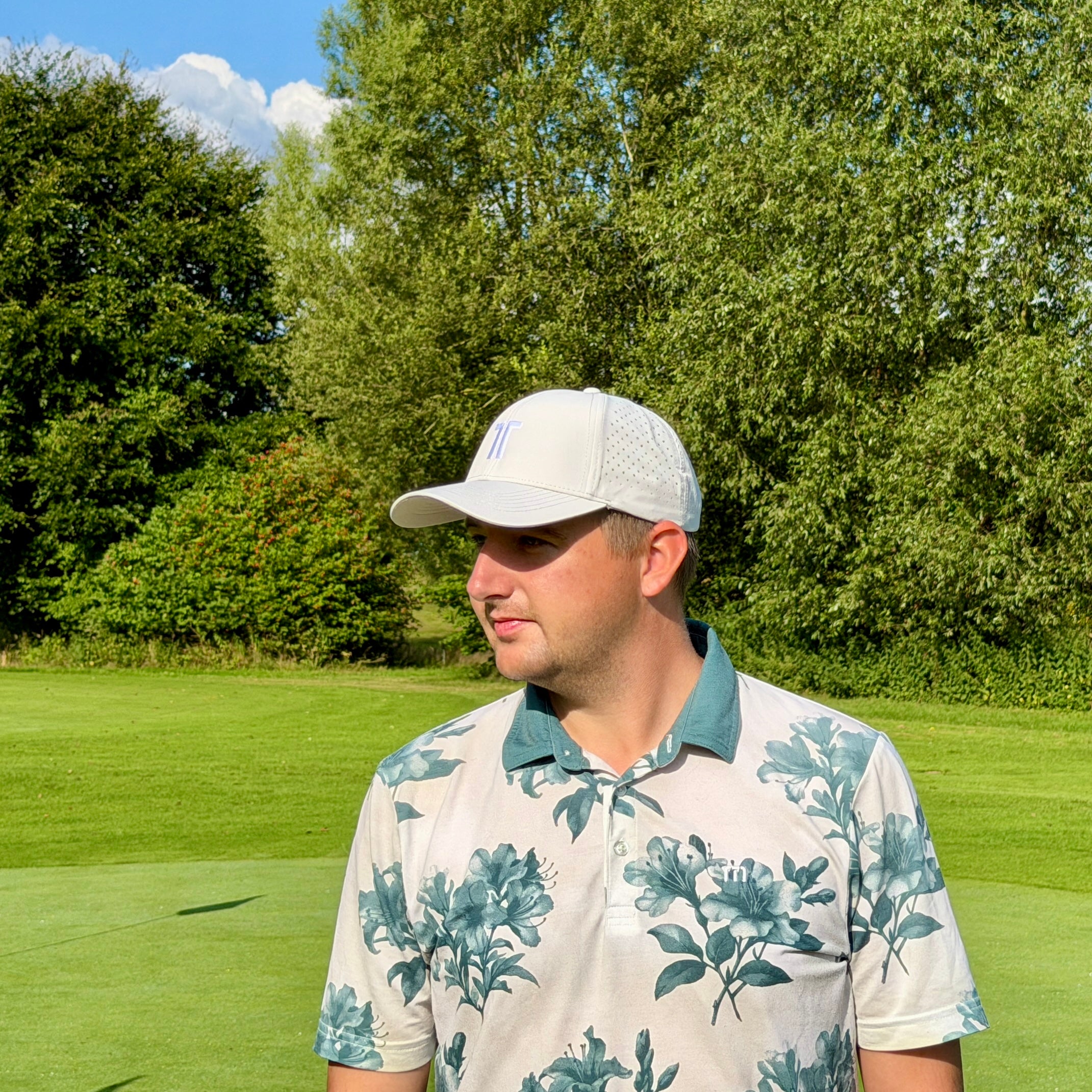 Person trägt THE CUTLINE Focus Cap in Weiß auf dem Golfplatz, Seitenansicht