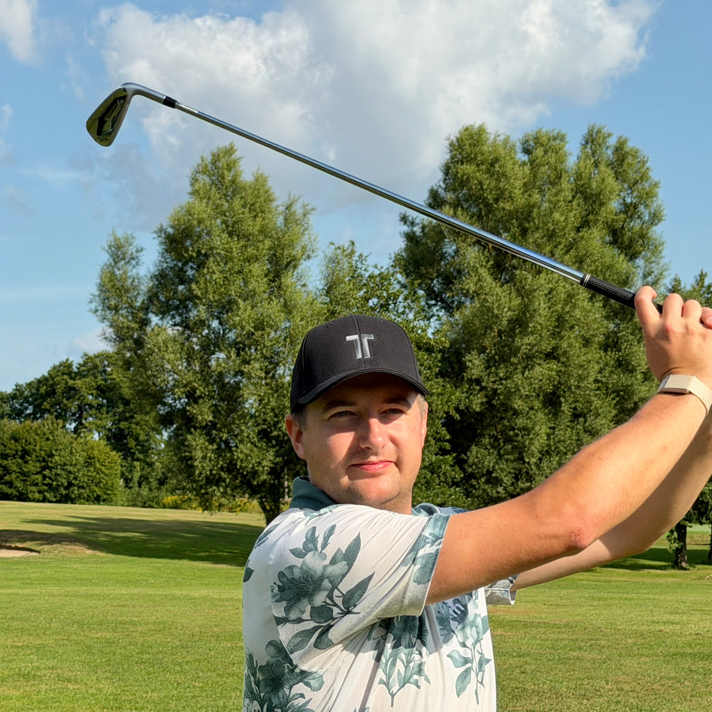 Person trägt THE CUTLINE Steady Cap in Schwarz beim Golfschwung