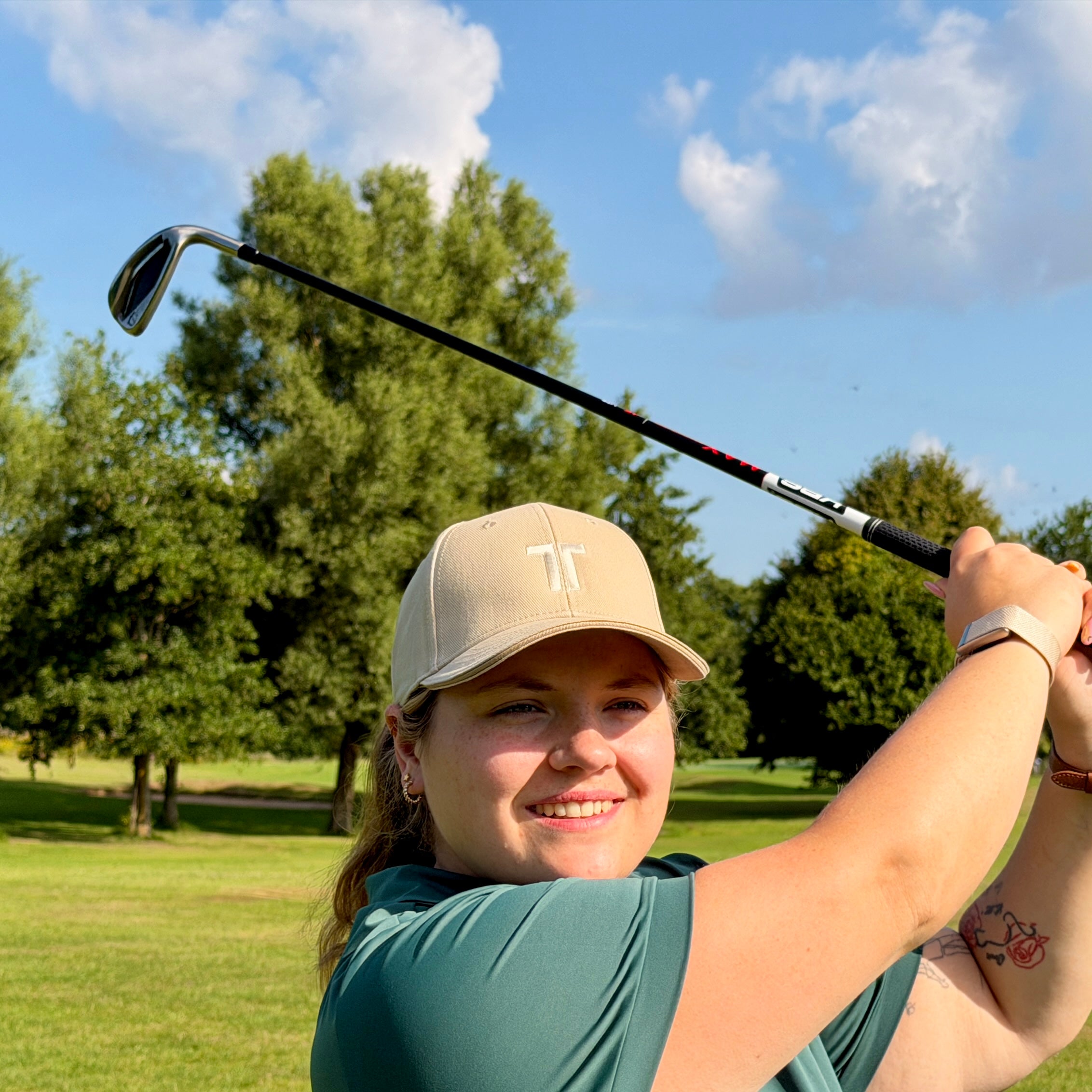 Person trägt THE CUTLINE Steady Cap in Sand beim Golfschwung